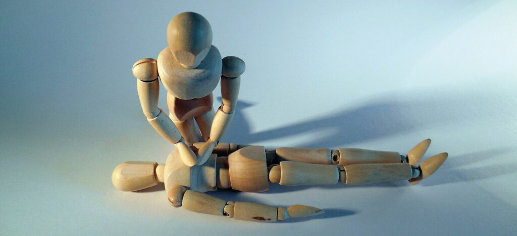 Two wooden mannequins applying CPR